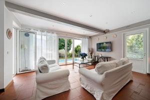 a living room with two white chairs and a table at Luxury Country House Domaso in Domaso