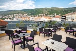 a patio with tables and chairs and a view of a city at Hotel Meduza in Senj