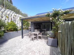 a patio with a table and chairs and a fence at Capricorn Studio Two - 150m to Solar Beach, Patio & Braai, Wifi, DSTV & Netflix in Plettenberg Bay
