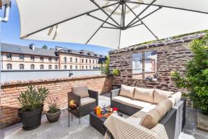 une terrasse avec un canapé, des chaises et un parasol dans l'établissement Maison Sévigné - Le calme du Thabor et la proximité du centre ville, à Rennes