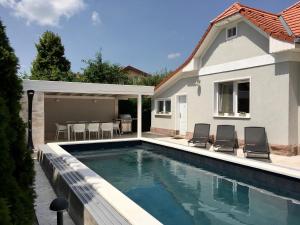 a swimming pool in front of a house at Vento Balaton in Alsóörs