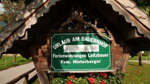 a sign in a park with flowers and a sidewalk at Loitzbauer Ferienwohnungen in Sankt Gilgen