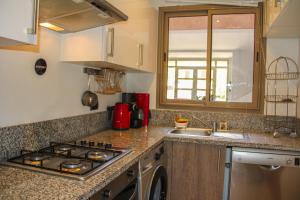 a kitchen with a stove top oven next to a sink at Modern Lakeview Apartment With Private Garden in Marrakesh