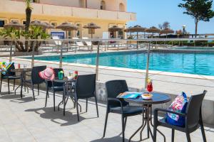a patio area with chairs, tables, chairs and umbrellas at Hotel Club Eloro in Noto Marina