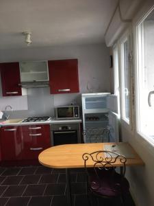 a kitchen with red cabinets and a wooden table at La source in Bagnoles de l'Orne