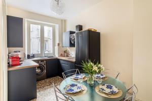 een keuken met een tafel met stoelen en een koelkast bij Le Traou Mad - Au cœur de l'Intra-muros in Saint-Malo