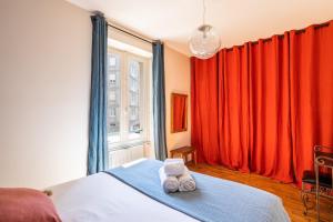sypialnia z czerwonymi zasłonami i łóżkiem z ręcznikami w obiekcie Le Traou Mad - Au cœur de l'Intra-muros w Saint-Malo
