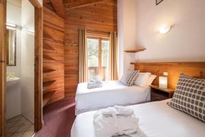 una camera d'albergo con due letti e un bagno di Madame Vacances Chalet Lea a La Tania