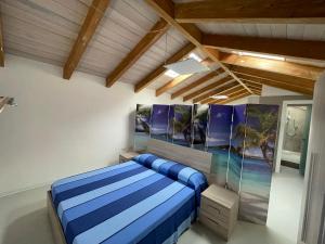 a bedroom with a blue bed and paintings on the wall at Loft Regina Margherita in SantʼAntìoco