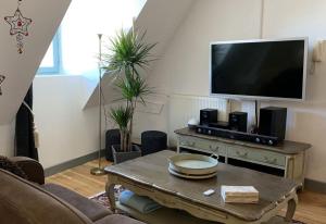 sala de estar con TV y mesa de centro en La Visitation - 30, en Orthez