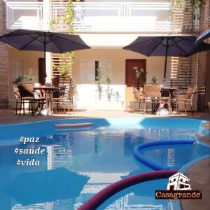 a pool with tables and umbrellas in a building at Casagrande Olímpia Hotel in Olímpia