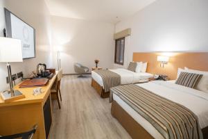 a hotel room with two beds and a desk at Aram Hotel - AlMeshael Exit 18 in Riyadh