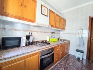 eine Küche mit einer Mikrowelle und einem Herd Top-Backofen in der Unterkunft Casa Rural Fuente de la Higuera in Ronda