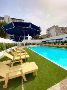 - une piscine avec des chaises longues, un parasol et une piscine dans l'établissement Vittoria Parc Hotel, à Bari