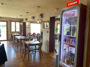 een restaurant met tafels en stoelen en een cocacola koelkast bij Dday House in Saint-Laurent-sur-Mer