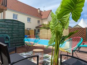 een patio met stoelen, een plant en een zwembad bij Dday House in Saint-Laurent-sur-Mer