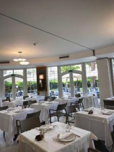 a restaurant with white tables and chairs and windows at Vittoria Parc Hotel in Bari