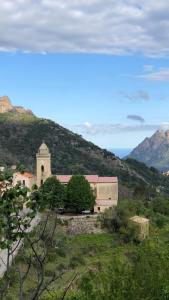 un edificio en una colina con montañas en el fondo en MAISON VILLAGE MARIGNANA, en Marignana