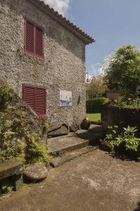 a stone house with red shuttered windows and stairs at Quinta do Mirante 1785 in Ponta Delgada