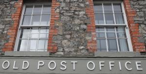 un antiguo letrero de la oficina de correos frente a un edificio de ladrillo en Old Post Office, en Slane