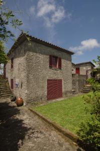 uma casa de pedra com uma porta vermelha e um quintal em Quinta do Mirante 1785 em Ponta Delgada