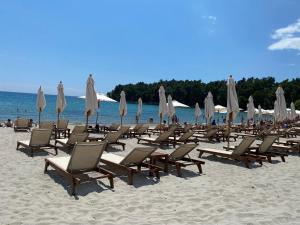 eine Gruppe von Liegestühlen und Sonnenschirmen am Strand in der Unterkunft Apartments Villa Viktoria in Tivat