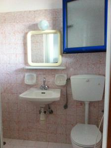 a bathroom with a sink and a toilet and a mirror at Oasis Azolimnos in Azolimnos Syros