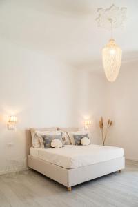 Cama blanca en habitación blanca con lámpara de araña en VALÚ, en Carloforte