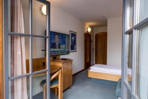 um quarto com uma cama e uma secretária com uma televisão em Hotel Edlingerwirt - Sauna & Golfsimulator inklusive em Spittal an der Drau