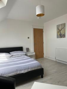 a white bedroom with a bed and a table at 14 Millstone Court in Portstewart