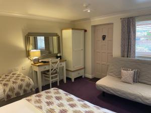 a bedroom with a bed and a desk and a mirror at The Old Fourpenny Hotel in Warwick