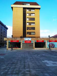 a large yellow building with red signs on it at LA TERRAZA DE LA FLORIDA terraza 225 m2 in Oviedo