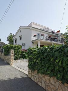 a white house with a balcony and a stone wall at Apartment Sara in Njivice