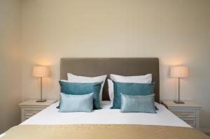 a bed with blue pillows and two lamps at Monte Santo Resort in Carvoeiro