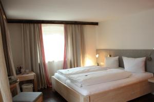 a bedroom with a large white bed with a window at Das Posch Hotel in Oberammergau