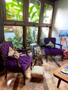a living room with purple chairs and a large window at Pousada Arte Urquijo in Paraty