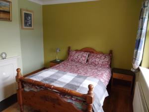 a bedroom with a wooden bed with a checkered blanket at Hannah's Cottage in Farranfore