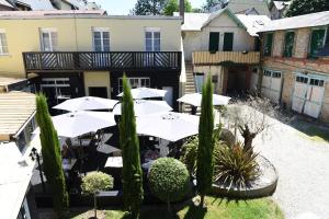 an outdoor restaurant with white umbrellas in a courtyard at Hôtel Normandie Spa in Bagnoles de l'Orne