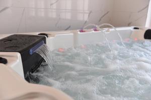 a bath tub filled with water with a shower at Hôtel Normandie Spa in Bagnoles de l'Orne