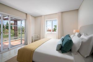 a bedroom with a large white bed and a balcony at Monte Santo Resort in Carvoeiro