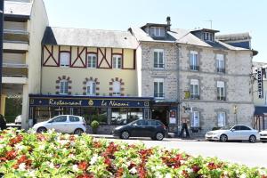 a building on a street with cars parked in front at Hôtel Normandie Spa in Bagnoles de l'Orne