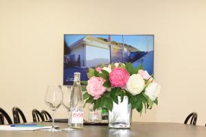 a vase of flowers on a table with wine glasses at Hôtel Normandie Spa in Bagnoles de l'Orne