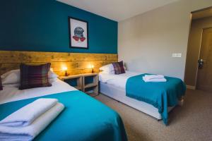 two beds in a room with blue walls at Union Road Moto Velo Accommodation in Crediton
