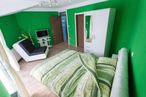 a green bedroom with a bed and a chair at Hostel Day 'N' Night in Niš