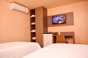 um quarto com duas camas e uma televisão na parede em Forte Express em Macapá