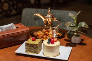 a table topped with a piece of cake and a plate of food at Aram Hotel - AlMeshael Exit 18 in Riyadh +37 photos