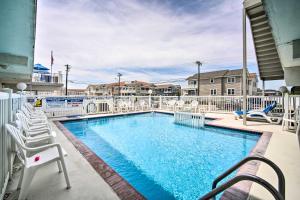a swimming pool with white chairs and a swimming poolvisor at Charming Oceanfront Condo, Walk to Wildwood Beach in Wildwood Crest