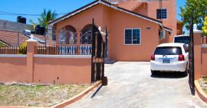 a car parked in front of a house with a gate at Bev's Rosevilla in Montego Bay