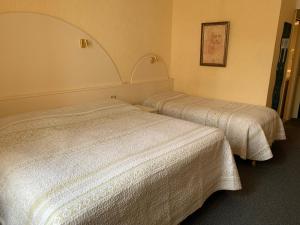 two beds in a hotel room with white sheets at Hotel Chiffre in Albi