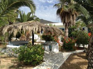 un patio con sombrilla de paja y algunas plantas en Oasis Apartments en Ios Chora